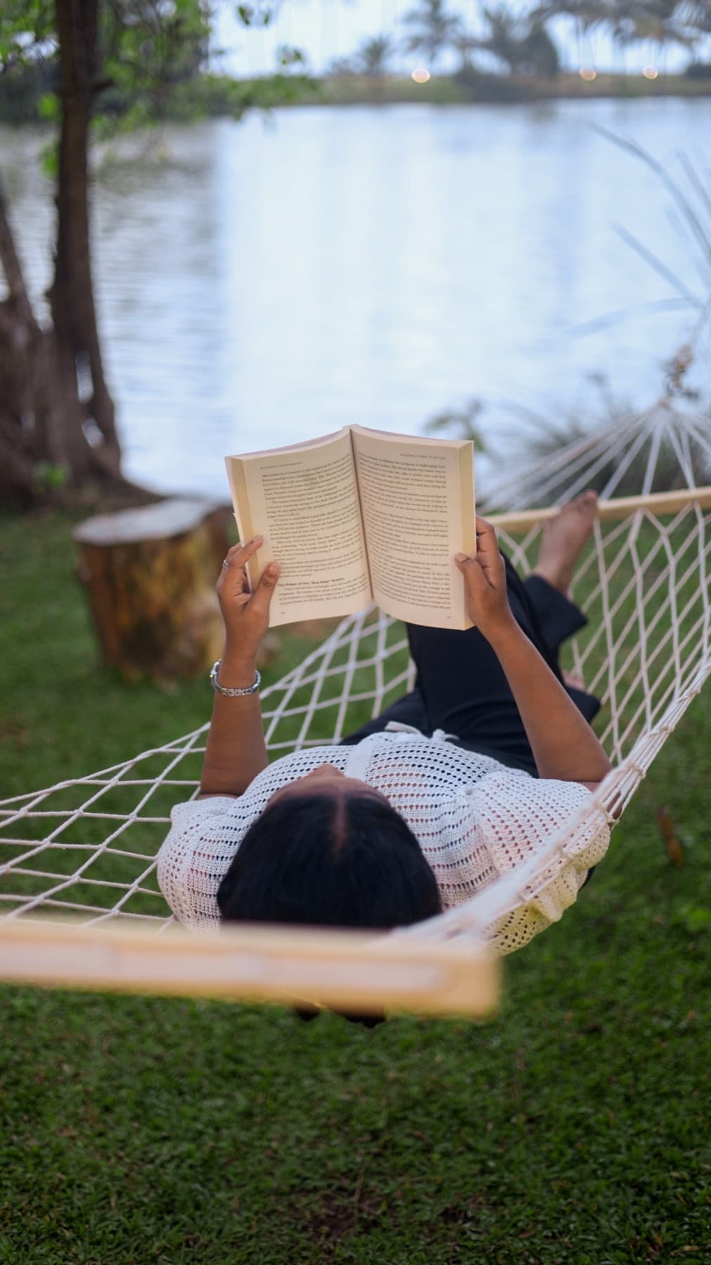 Guest reading in a riverside hammock at River Loom